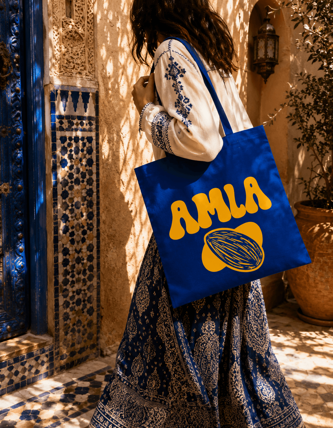 Tote bag AMLA bleu majorelle porté dans une ruelle marocaine